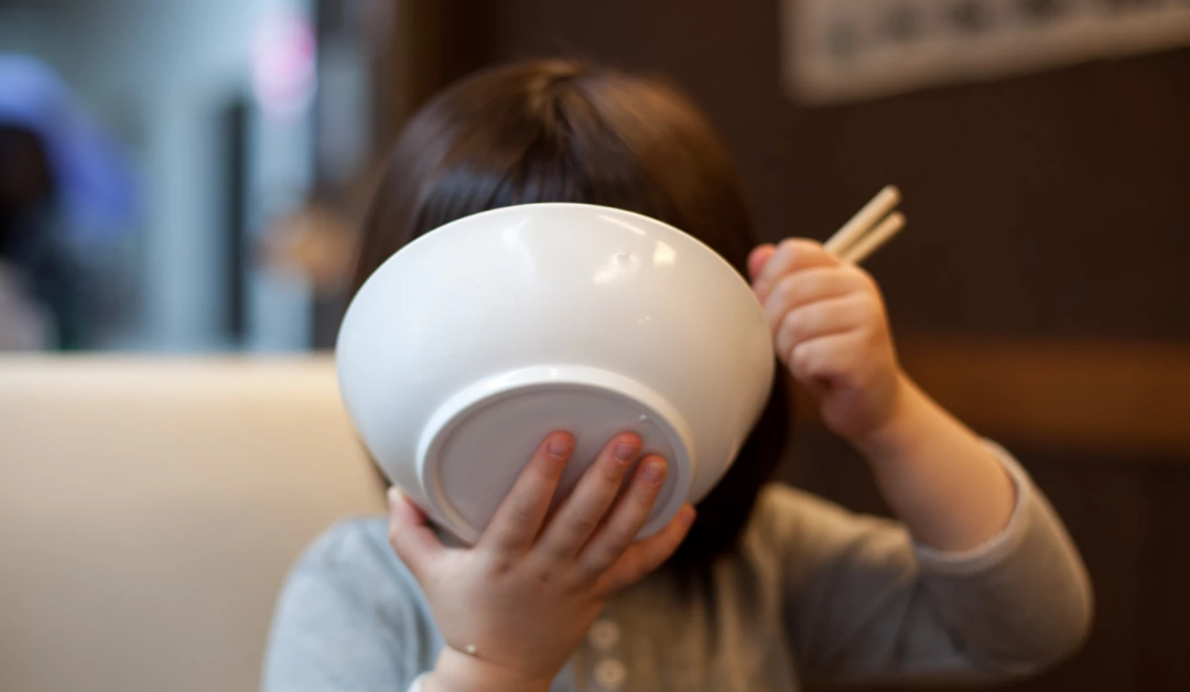 young girl eating noodles from a bowl