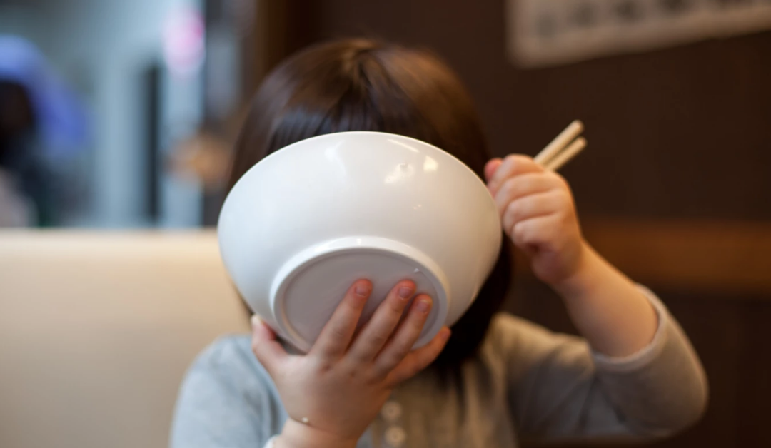 niña comiendo fideos de un tazón